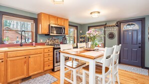 A kitchen with wooden cabinets, a microwave, a sink, and a dining table with chairs.
