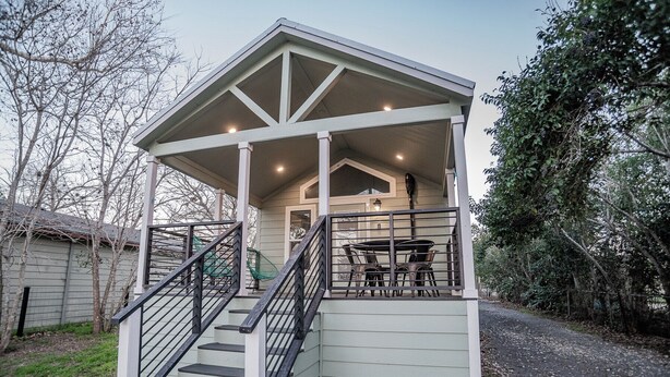 A covered porch with a staircase leading to a seating area with chairs and a table.