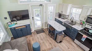A modern kitchen with a large island, built-in appliances, and a dining area with a sofa and ottoman.