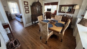 A dining area with a wooden table, wicker chairs, and a vintage armoire.