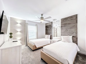 Een moderne slaapkamer met een bed, nachtkastjes, een plafondventilator en een grote spiegel.