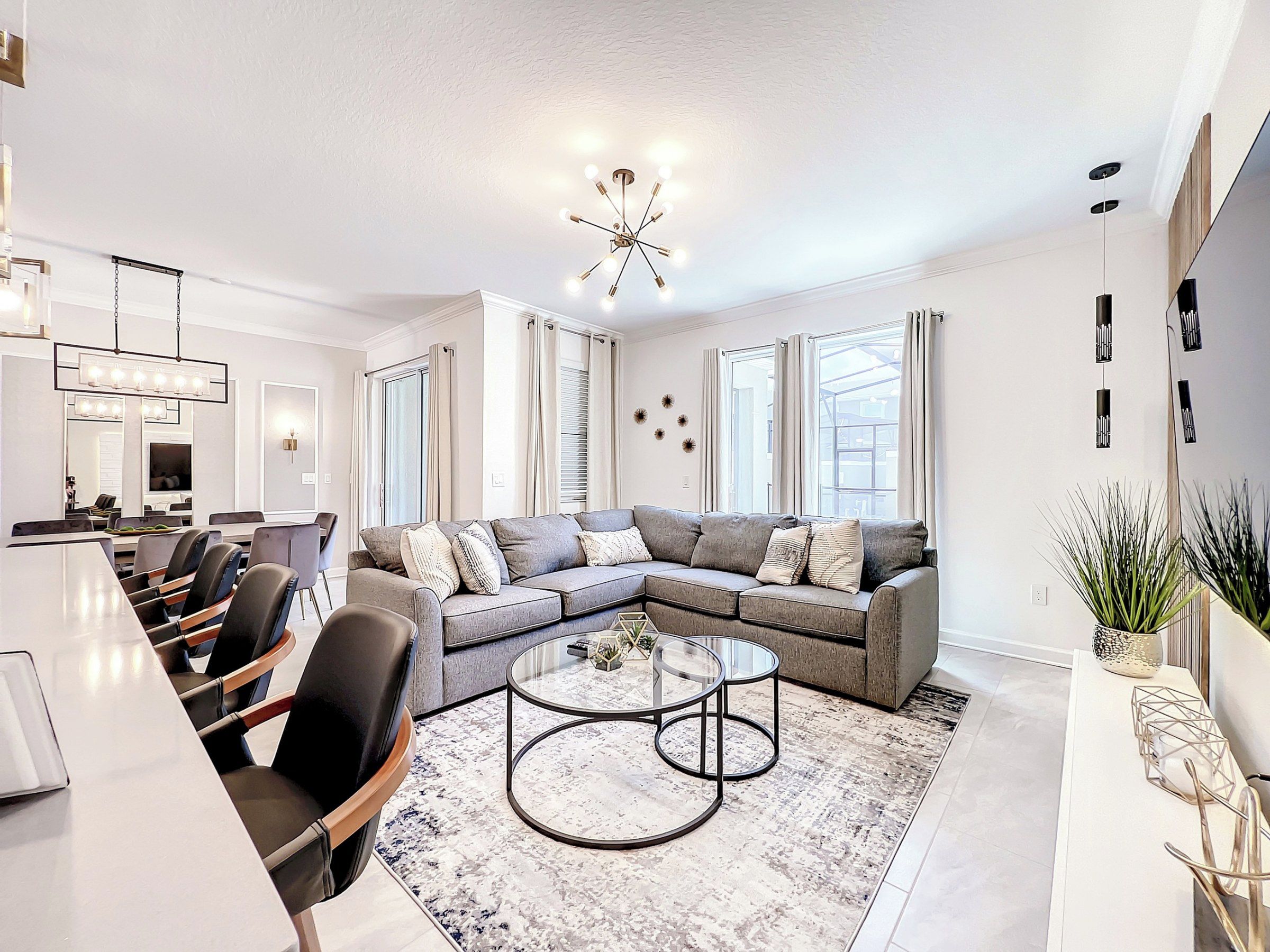 Un salon moderne avec un canapé d’angle, une table basse en verre et un coin repas comprenant des chaises et une table.