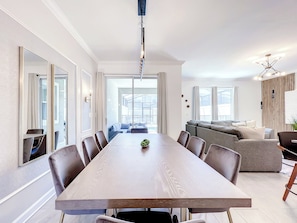 Een moderne eetruimte met een lange tafel, meerdere stoelen en uitzicht op het terras.