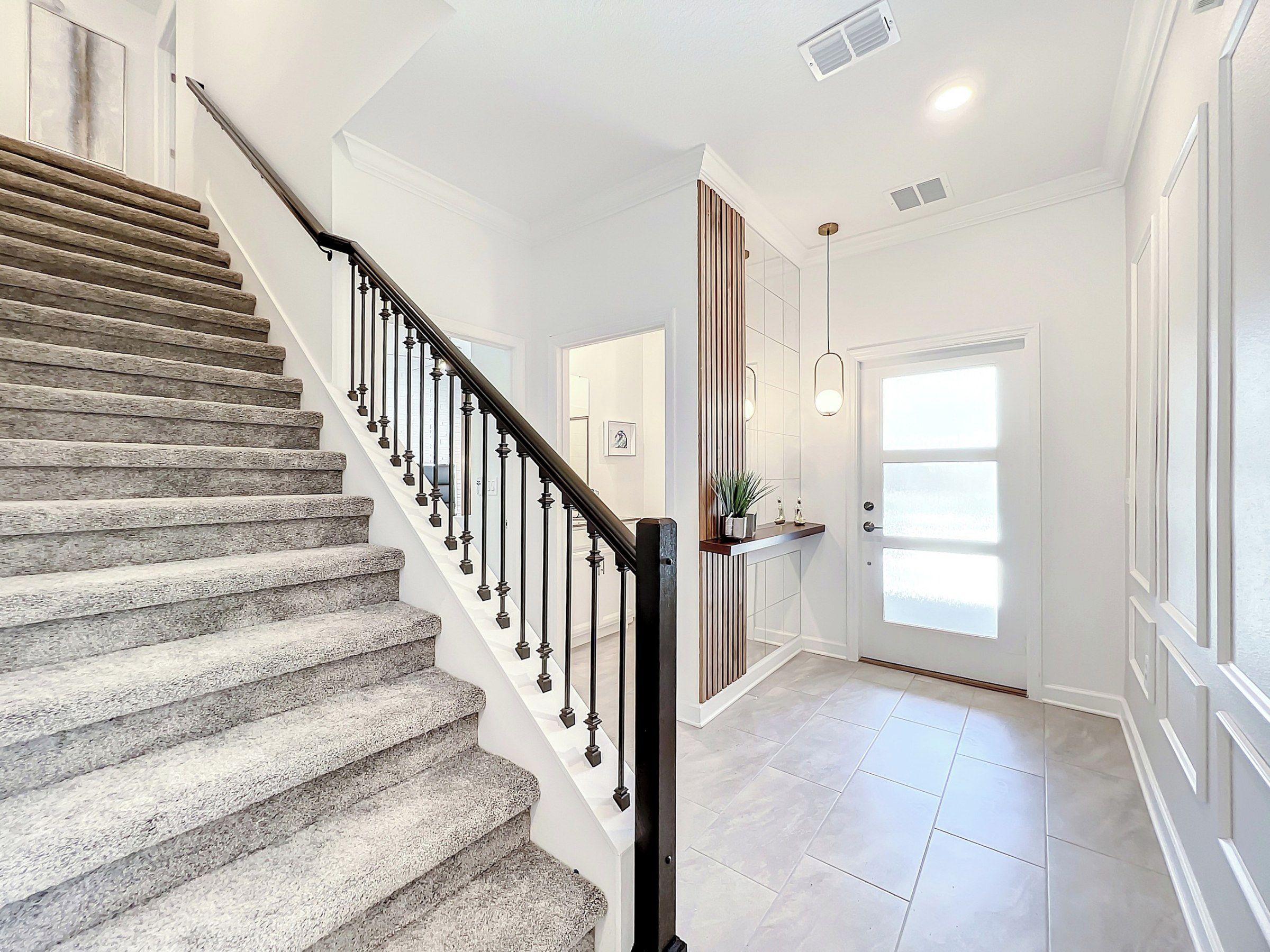 Un escalier avec une rampe et une porte dotée de panneaux en verre dépoli.