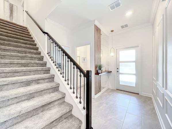 Bright foyer with carpeted staircase and modern accent wall