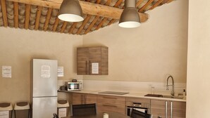 Een moderne keuken met houten balken, een koelkast, magnetron, gootsteen en een eethoek met stoelen en een tafel.