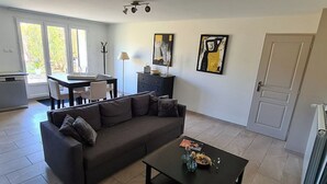 Een moderne woonkamer met een donkere bank, een salontafel en kunstwerken aan de muren.