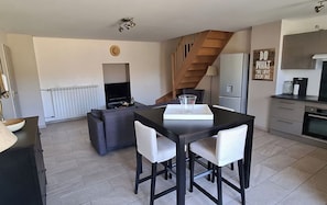 Un appartement moderne comprenant un coin repas, une cuisine, un salon et un escalier.