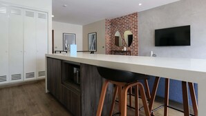 A modern kitchen with a white countertop, dark wood cabinets, and a brick accent wall.