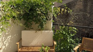 Un pati amb una cadira de fusta, una taula petita i una planta en test.