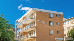 A multi-story building with balconies, a clear sky, and the name 'CRYSTAL WATERS' on the side. - Crystal Waters 2, 2 Munster Street (PORT MACQUARIE)