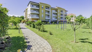 A multi-story residential building with balconies, a paved pathway, and small trees. - ADRIA house with apartments / Adria APARTMENT C3 (Umag)