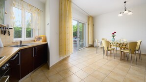 A modern kitchen with a dining area, large windows, and a sliding glass door leading to an outdoor space. - ADRIA house with apartments / Adria APARTMENT C3 (Umag)