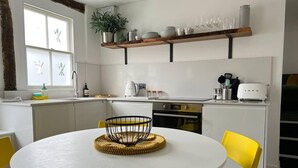 A modern kitchen with white cabinets, a round table, yellow chairs, and a built-in oven. - 2 Bed Grade 2 - Dates Back to 1500's (Colchester)