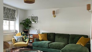 A living room with a green sofa, a yellow armchair, a glass coffee table, and a potted plant. - 2 Bed Grade 2 - Dates Back to 1500's (Colchester)