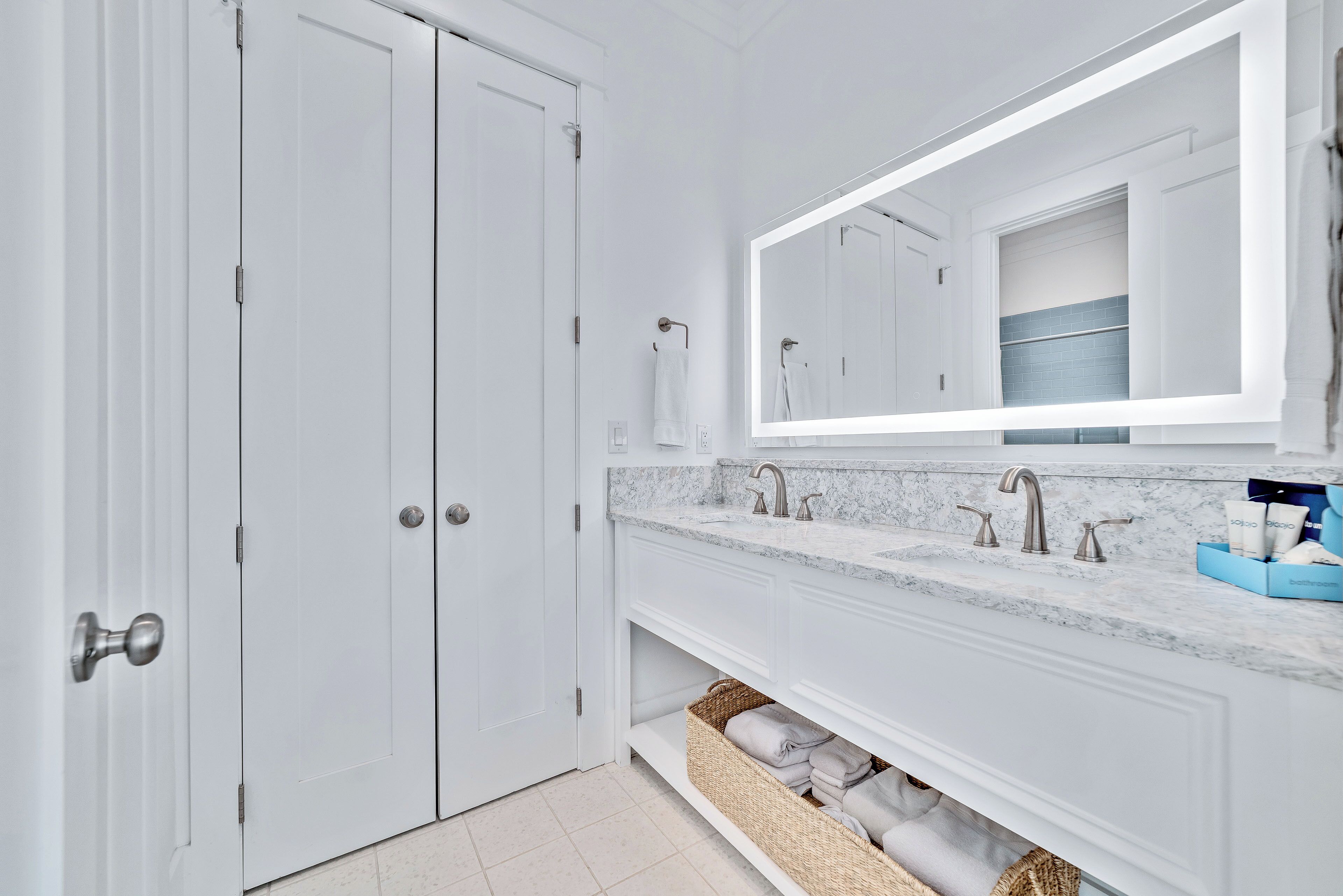 A modern bathroom with a double vanity, a large mirror, and a built-in storage basket.