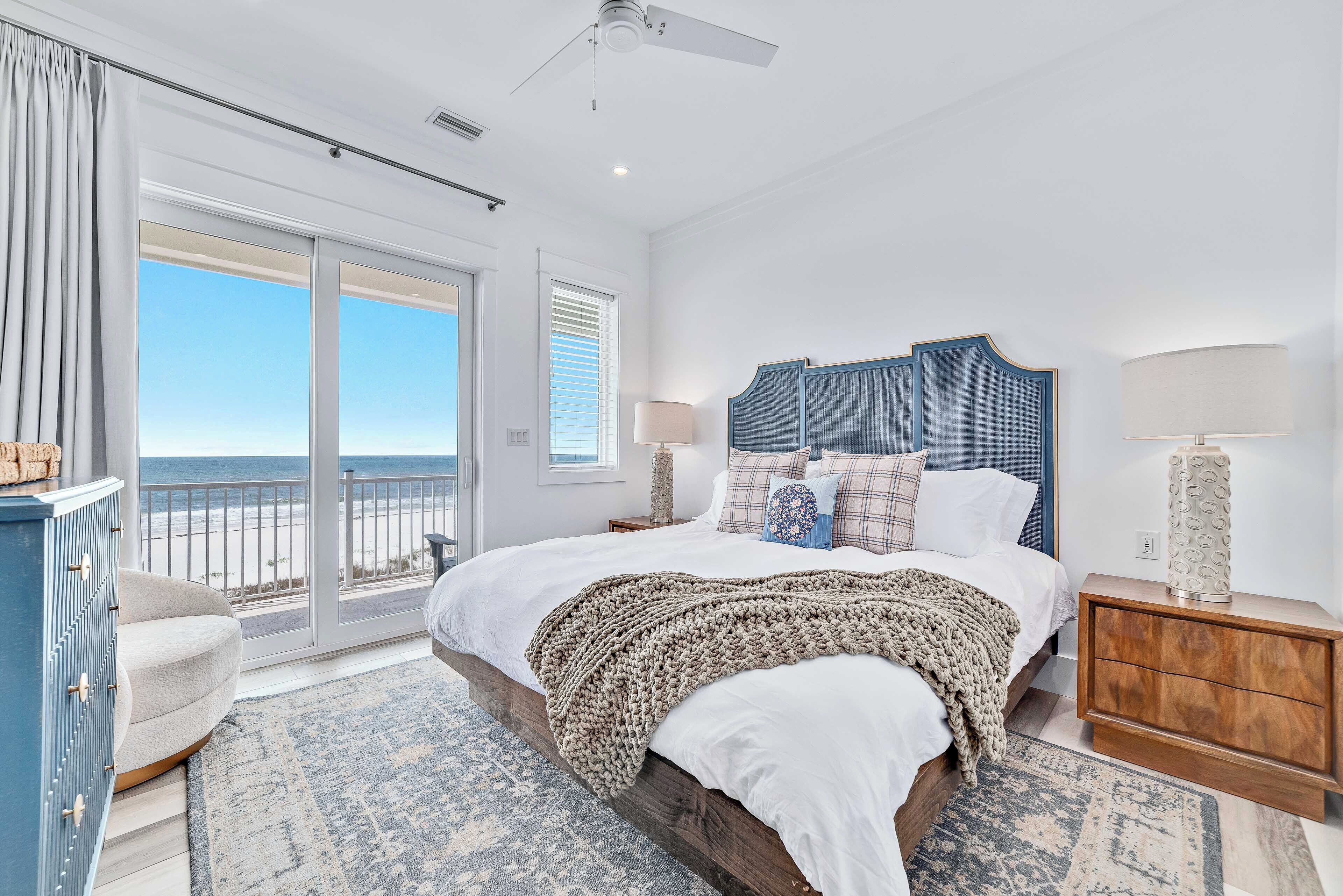 A bedroom with a large bed, a view of the beach, and a balcony.