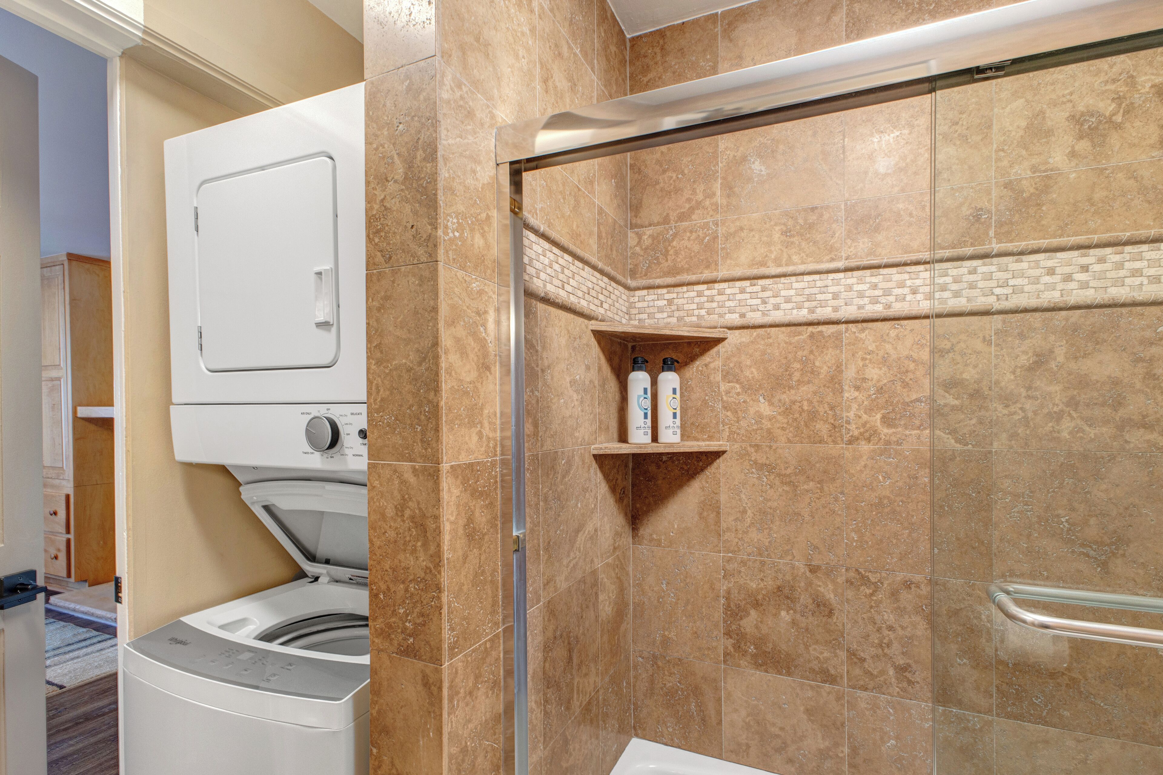 A bathroom with a shower, a toilet, and a washing machine.