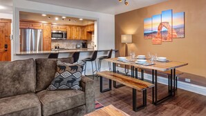 Una cocina moderna con armarios de madera, electrodomésticos de acero inoxidable y un comedor con mesa y bancos de madera.