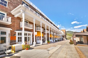 A row of brick buildings with white balconies and a covered walkway.