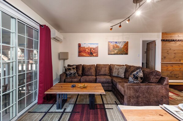 A modern living room with a sectional sofa, a wooden coffee table, and two paintings on the wall.