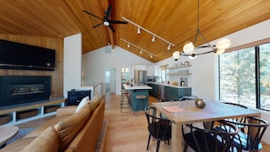 A modern kitchen with a central island, wooden ceiling, and large windows. - Forest Retreat with Access to Exclusive Golf (Sunriver)