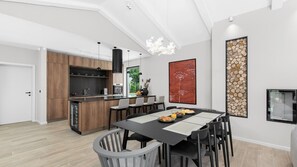A modern kitchen with wooden cabinets, a central island, and a dining area with a black table and chairs.