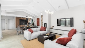Ein modernes Wohnzimmer mit zwei grauen Sofas, einem dunklen Couchtisch und einer Küche im Hintergrund.