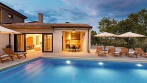 Ein modernes Haus mit Schwimmbad, Sitzgelegenheiten im Freien und Essbereich.