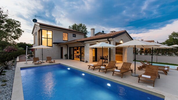 Una casa moderna con piscina, mobiliario exterior y un jardín bien cuidado.