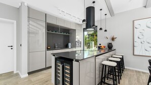 Una cocina moderna con una isla central, taburetes de bar e iluminación colgante.