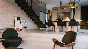 Een moderne leefruimte met een trap, zwarte stoelen, een eethoek en kunstwerken aan de muren.