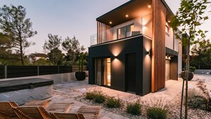Een modern huis met twee verdiepingen, een plat dak, grote ramen en een goed verlichte gevel.