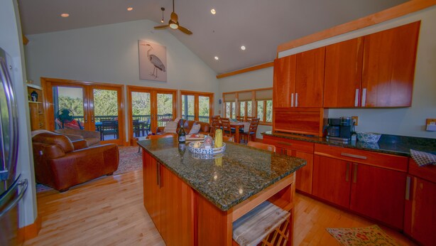 A spacious kitchen with wooden cabinets, a granite countertop, and a dining area with a large window. - Captivating Cabana – Luxury home, Boat Slip, Golf Cart, Pool, Pickleball, & Club (North Captiva)