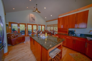 A spacious kitchen with wooden cabinets, a granite countertop, and a dining area with a large window.