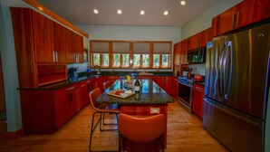 Una cocina moderna con armarios de madera, un refrigerador de acero inoxidable y una isla central con taburetes de bar.