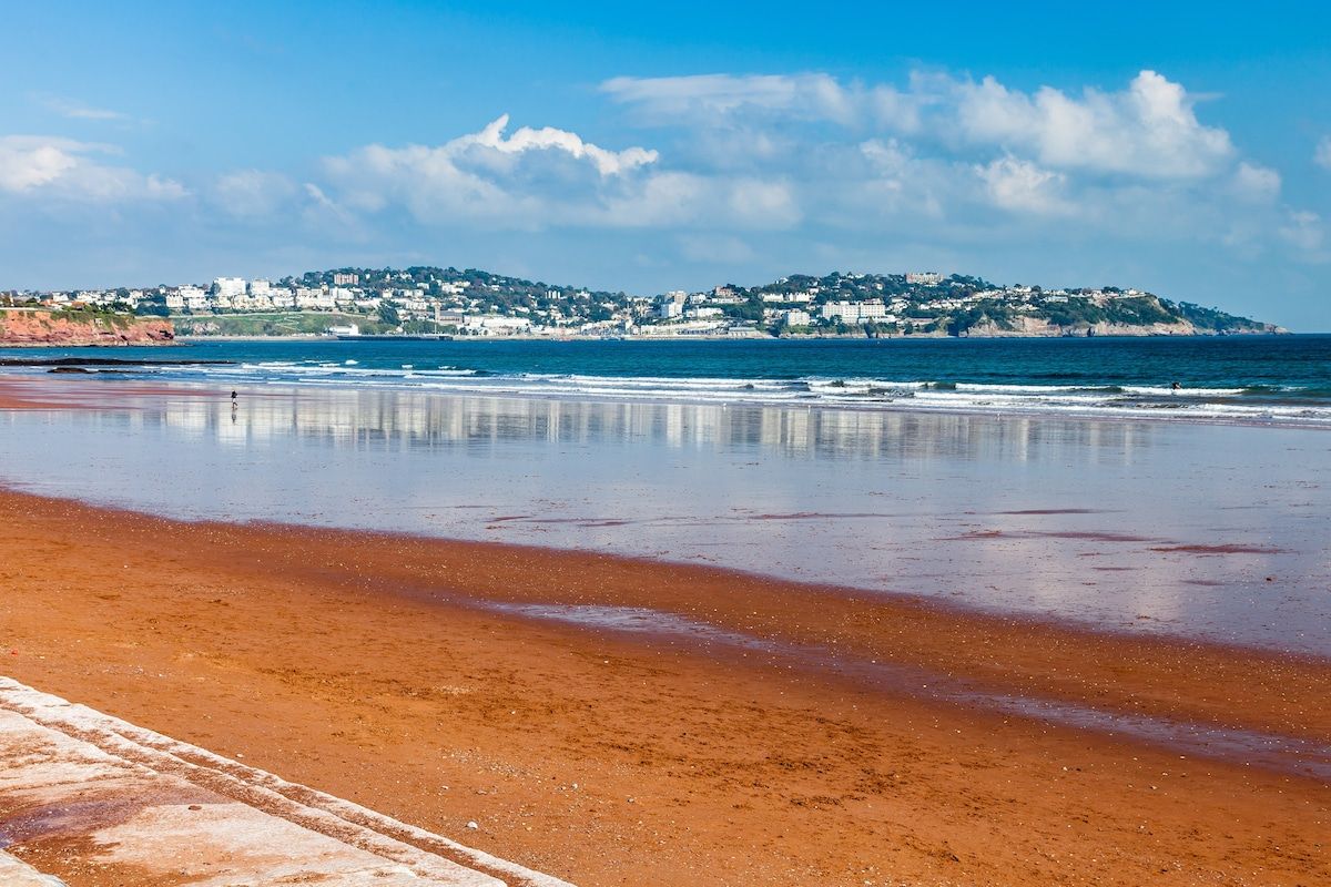 A beach with a clear view of a coastal town in the background.