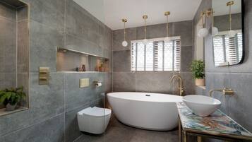 A modern bathroom with a freestanding bathtub, a white sink, and a large mirror.