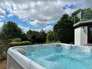 A hot tub in a garden with a clear sky. - The Spinney (Paignton)
