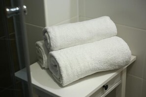Two white towels stacked on a white bathroom counter. - Prosta Butelkowa (Torun)
