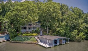 Un chalet au bord du lac, doté d’un quai, et entouré d’une forêt dense.