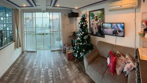 A living room with a sofa, a Christmas tree, and a TV on the wall. - Pousada Graff (Penha)