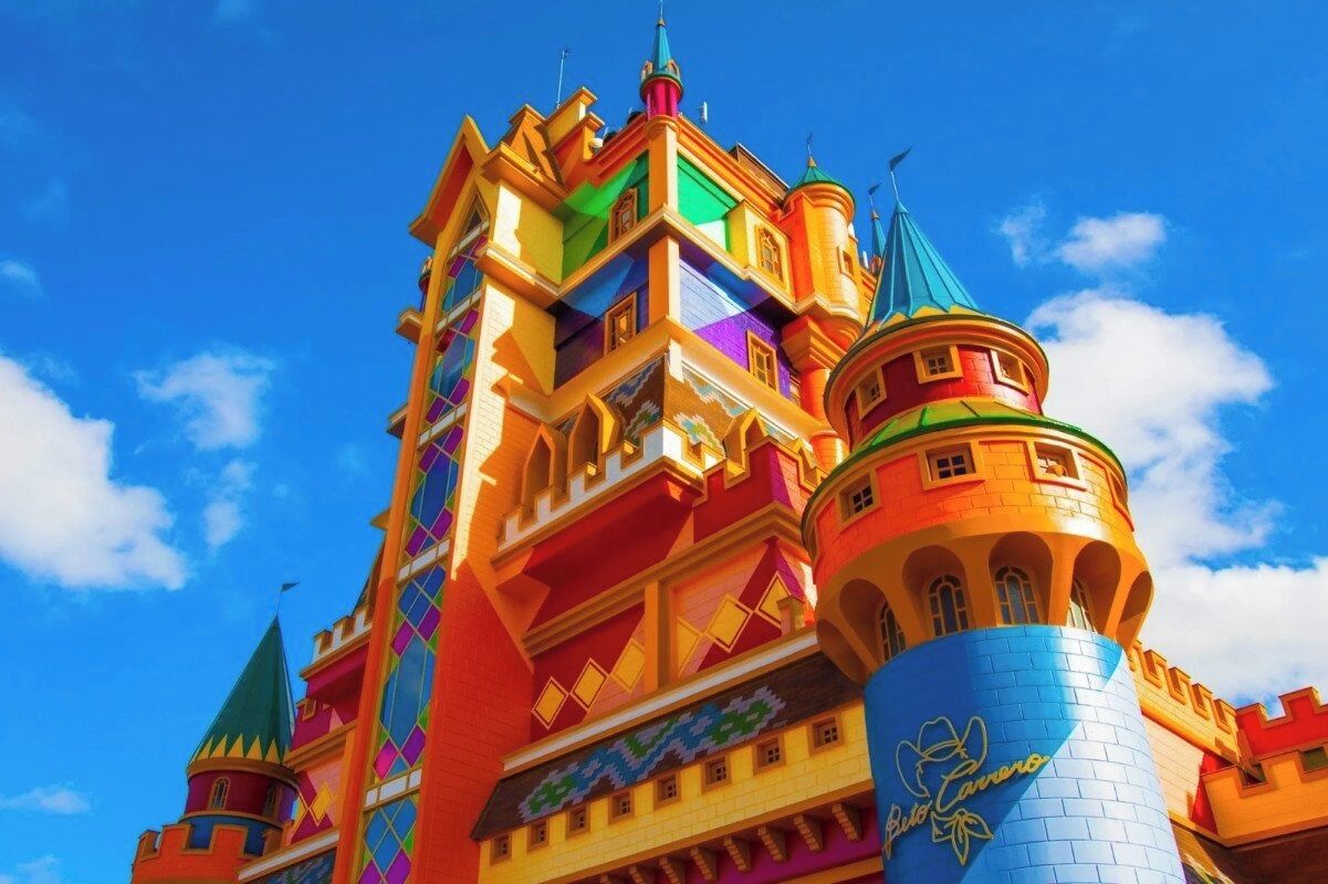 Un edificio colorato simile a un castello, con diverse torri e una torre cilindrica ben visibile con base blu.