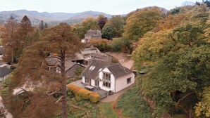 A white building with a sloped roof, surrounded by trees and hills in the background. - Barakat Lakes Escape | Ridgestone (Ambleside)