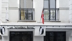 Fachada del Hotel UK Estambul, con grandes puertas dobles negras y un cartel sobre la entrada.