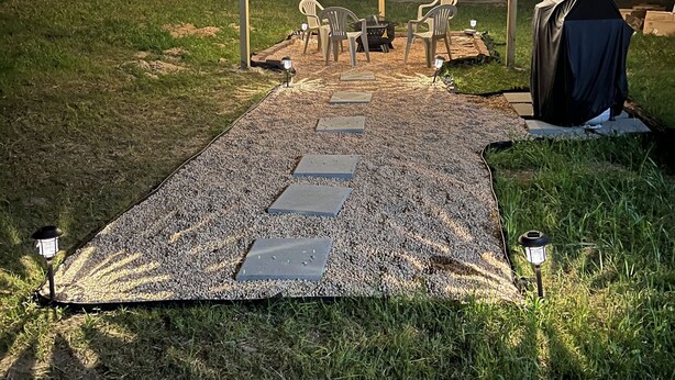 An outdoor seating area with chairs and a fire pit, illuminated by string lights and lanterns.