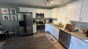 A modern kitchen with white cabinets, stainless steel appliances, and a granite countertop.