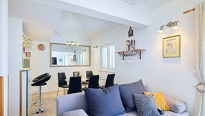 A modern living room with a grey sofa, a dining area with a large mirror, and a kitchen visible in the background. - Joyful Place (Dubrovnik)