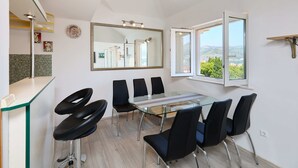 A modern kitchen with a glass dining table, black chairs, and a large mirror. - Joyful Place (Dubrovnik)