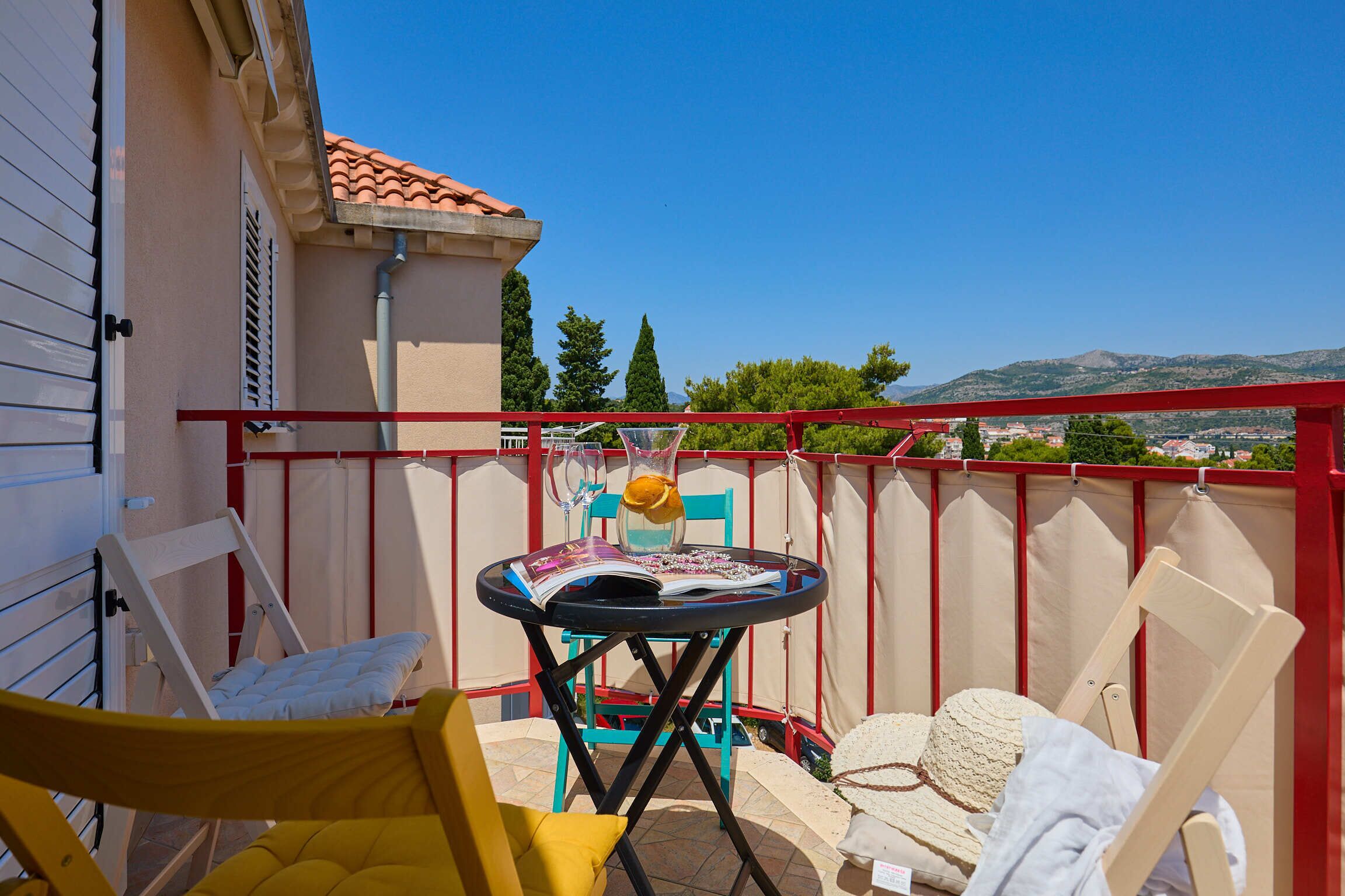 A balcony with a table, chairs, and a view of the landscape.